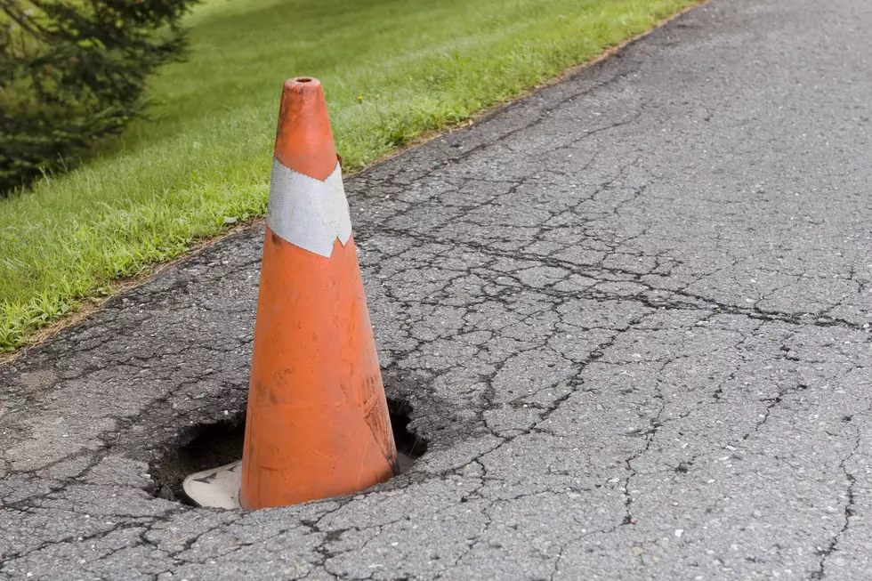 Pot hole in the road with an orange cone inside